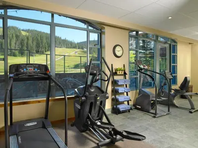 a gym with two treadmills and two elliptical machines at Sundance Lodge in Sun Peaks