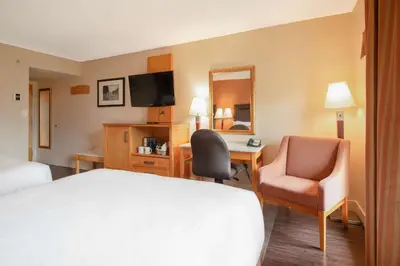 a hotel room with a bed and a desk and a chair at Coast Hillcrest Hotel in Revelstoke