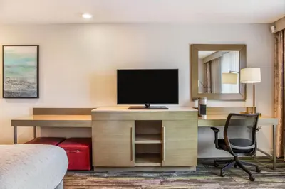 a hotel room with a desk with a television and a chair at Ramada by Wyndham St Paul AB in St. Paul