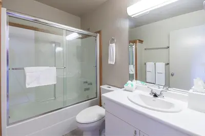 a bathroom with a sink and a shower and a toilet at Himwitsa Lodge in Tofino