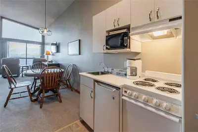 a kitchen with a sink and a table with chairs at Himwitsa Lodge in Tofino