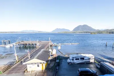 a dock with a rv and a truck parked on the water at Himwitsa Lodge in Tofino