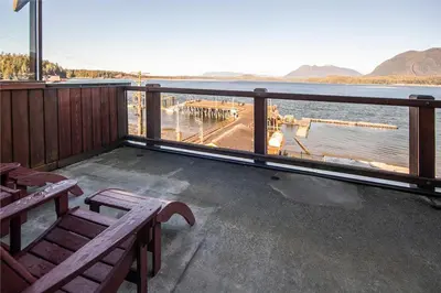a balcony with a bench and a view of the water at Himwitsa Lodge in Tofino