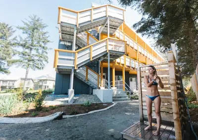 a woman in a bathing suit standing in front of a building at Pacific Sands Beach Resort in Tofino