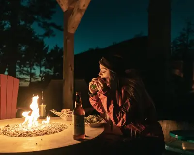 a woman sitting at a table with a bottle of wine at Pacific Sands Beach Resort in Tofino