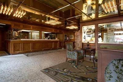 a lobby with a chair and a person in a mirror at Crest Hotel in Prince Rupert