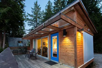 a wooden cabin with a large glass door on a deck at Backeddy Resort and Marina in Egmont