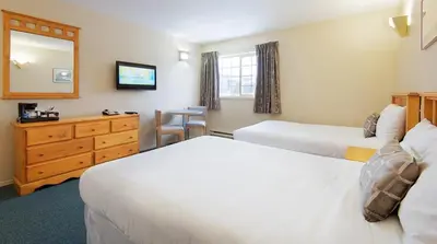 a hotel room with two beds and a mirror at Fernie Slopeside Lodge in Fernie
