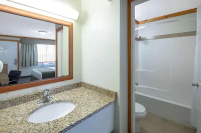 a bathroom with a sink and a mirror and a toilet at Travelodge by Wyndham Golden Sportsman Lodge in Golden