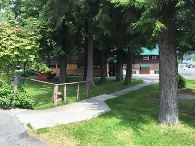 a park with a bench and trees and a building at Copper River Motel in Terrace