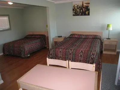 a hotel room with two beds and a table at Beach Grove Motel in Tsawwassen