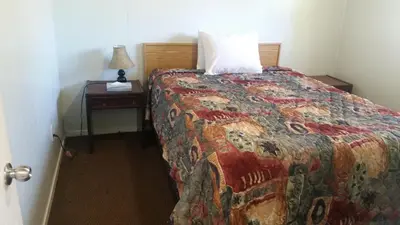 a bedroom with a bed with a pillow and a night stand at Holiday House Motel in Penticton