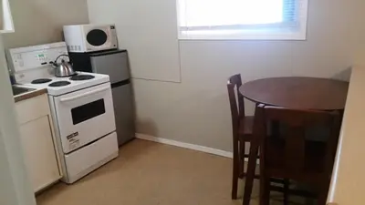 a kitchen with a stove and a table and a microwave at Holiday House Motel in Penticton