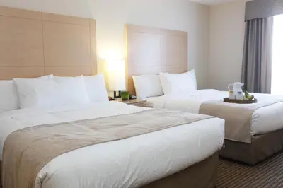 a hotel room with two beds and a window at Vegreville Suites in Vegreville