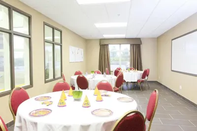 a conference room with tables and chairs with white tablecloths at Vegreville Suites in Vegreville