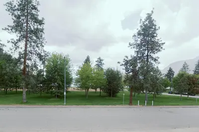 a park with trees and a field with a road at Waterfront Inn in Penticton