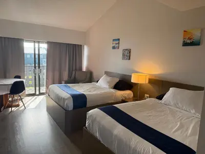 a hotel room with two beds and a desk at Sand Pebbles Inn in Qualicum Beach