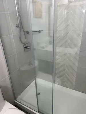 a shower with a glass door in a bathroom at Sand Pebbles Inn in Qualicum Beach