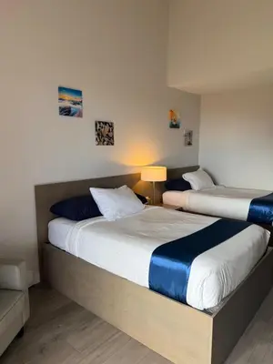 two beds in a hotel room with a lamp at Sand Pebbles Inn in Qualicum Beach