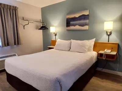 a hotel room with a large bed with white sheets at Fireweed Motel in Smithers