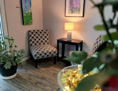 a living room with a chair and a table with a lamp at Fireweed Motel in Smithers