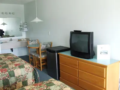 a hotel room with a bed and a tv on a dresser at Ponderosa Motor Inn in Golden
