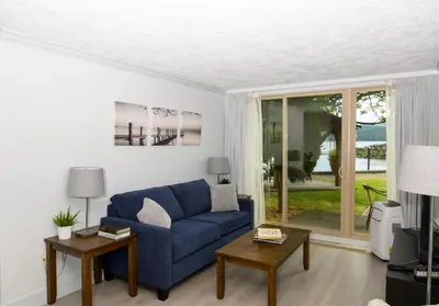 a living room with a blue couch and a window at Oceanfront Suites at Cowichan Bay in Cowichan Bay