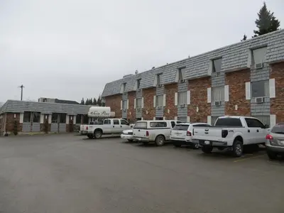 a parking lot with cars parked in front of a building at Twin Pine Inn & Suites in Hinton