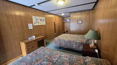 a hotel room with two beds and a desk at Black Cat Guest Ranch in Brule Mines