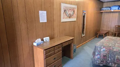 a room with a bed and a dresser and a desk at Black Cat Guest Ranch in Brule Mines