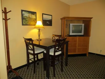 a room with a table and chairs and a television at Athabasca Valley Inn & Suites in Hinton