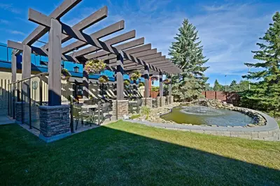 a garden with a pond and a wooden pergola at Best Western Wayside Inn in Wetaskiwin