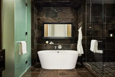 a bathroom with a large tub and a mirror at Rosewood Hotel Georgia in Vancouver
