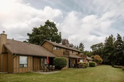 a house with a porch and chairs in the yard at Beach Acres Resort in Parksville