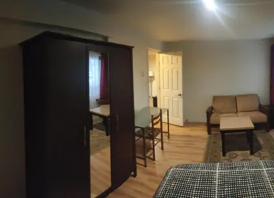 a bedroom with a door open to a room with a table at Black Rooster Guesthouse in Prince Rupert