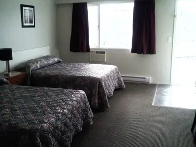 a hotel room with two beds and a window at Caravan INN in Quesnel