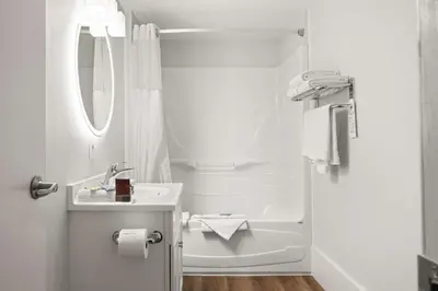 a white bathroom with a shower and a sink at SureStay Hotel by Best Western Rossland Red Mountain in Rossland