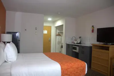 a hotel room with a bed and a kitchen at Howard Johnson by Wyndham Fort St. John in Fort Saint John