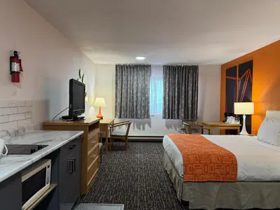 a hotel room with a bed and a kitchen and a television at Howard Johnson by Wyndham Fort St. John in Fort Saint John