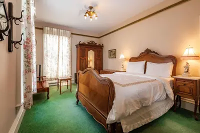 a bedroom with a large bed and green carpet at Amethyst Inn in Victoria