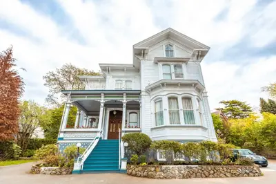 a white house with blue stairs and a car in front at Amethyst Inn in Victoria
