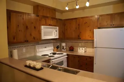 a kitchen with wooden cabinets and a white refrigerator at Whistler Superior Properties in Whistler