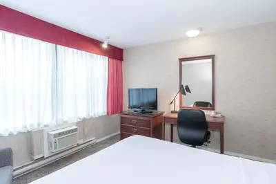 a hotel room with a bed and a desk and a mirror at Sandman Hotel Penticton in Penticton