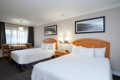 a hotel room with two beds and a desk at Sandman Hotel Revelstoke in Revelstoke