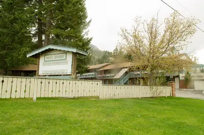 a fence in front of a house with a building at Motel Bavaria in Radium Hot Springs