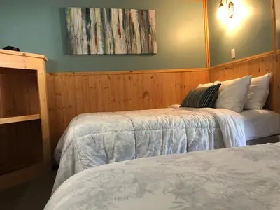 a bedroom with two beds and a painting on the wall at Piccadilly Motel in Radium Hot Springs