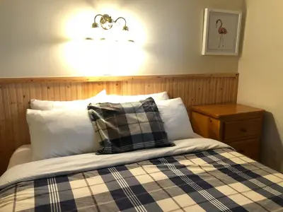 a bed with a plaid blanket and a light above it at Piccadilly Motel in Radium Hot Springs