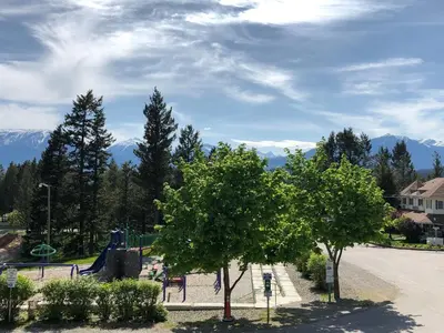 a playground with a slide and trees and mountains at Piccadilly Motel in Radium Hot Springs