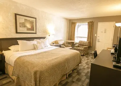 a hotel room with a large bed and a chair at Crystal Springs Lodge in Radium Hot Springs