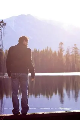 a man standing in front of a lake at Crystal Springs Lodge in Radium Hot Springs